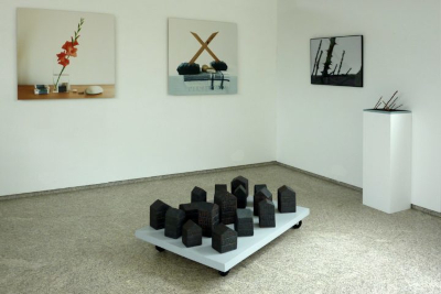 Imagen del interior de la sala de exposición del taller de Caxigueiro. En primer plano una pieza de cerámica, en la pared del fondo varias fotografías y a un lado una pieza más pequeña